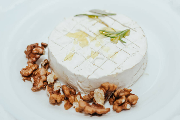Round camembert cheese with olive oil, rosemary and nuts. - Foto, Bild
