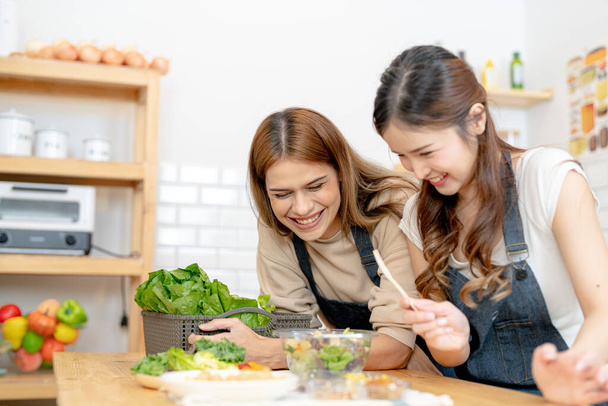 Усміхнені жінки готують свіжі здорові салатні овочі. жінка сидить у коморі на красивій інтер'єрній кухні. Чиста дієта харчування з місцевих продуктів та інгредієнтів Ринок свіжий
. - Фото, зображення