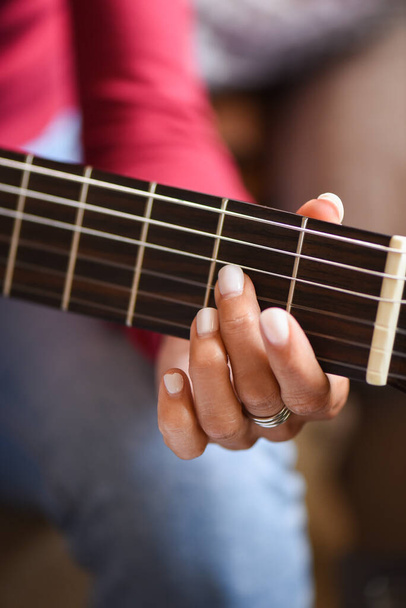 detail ruky na kytaře, ženské prsty s bílými porcelánovými nehty. Fuchsia růžový dres v pozadí, popředí detail klasické kytary. - Fotografie, Obrázek
