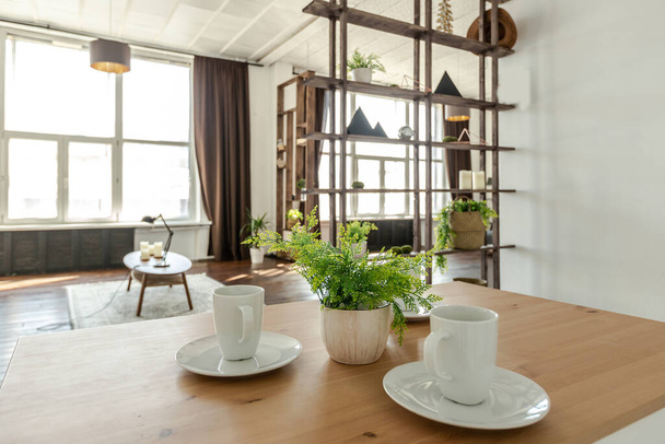 studio spacieux décoré avec du bois et du blanc. Design minimaliste avec d'énormes fenêtres à la lumière du soleil. coin cuisine et salon - Photo, image