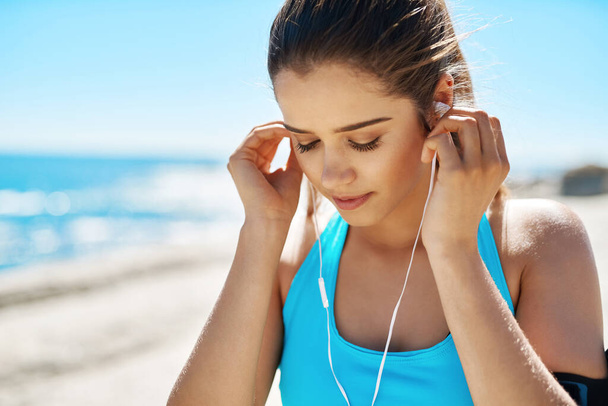 Μπαίνουμε σε κατάσταση τέρατος. μια αθλητική νεαρή γυναίκα που ακούει μουσική ενώ είναι έξω για προπόνηση - Φωτογραφία, εικόνα