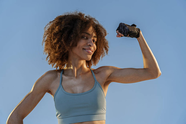 Urheilupukuinen nainen näyttää lihaksiaan studion taustalla. Harjoitustulokset - Valokuva, kuva