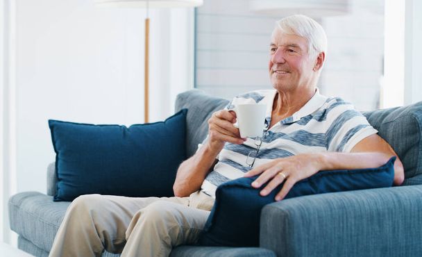 Стільки хороших спогадів. старший чоловік розслабляється з чашкою кави на дивані вдома
 - Фото, зображення