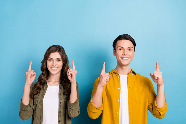 Portrait photo of cheerful good mood smiling couple friendship wear shirts direct fingers mockup university advert isolated on blue color background. - Φωτογραφία, εικόνα
