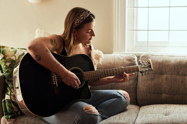 Algunas personas hablan en acordes. una joven tocando una guitarra en un día relajante en casa - Foto, imagen