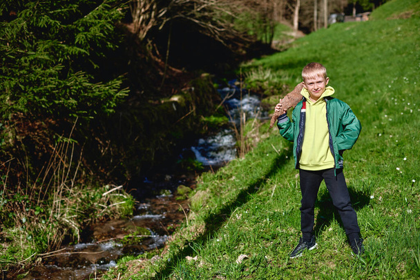 Egy kisfiú sétál a hegyi folyón. A tiszta vízen keresztül megvizsgálja a kavicsokat a folyó fenekén. - Fotó, kép