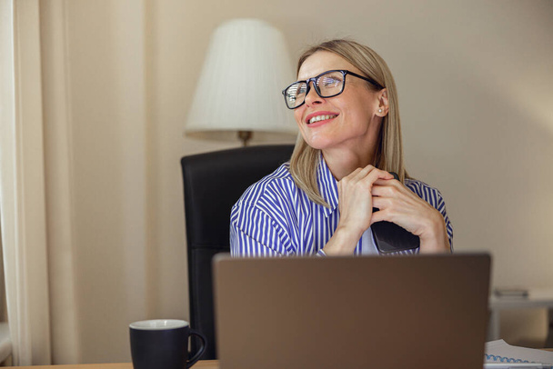 Attractive woman freelancer working on laptop from home office. High quality photo - Foto, afbeelding