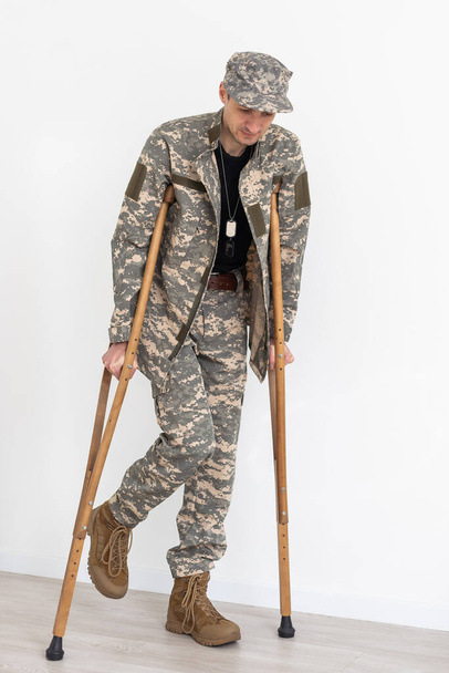 Portrait of soldier with crutches against white background. - Фото, зображення