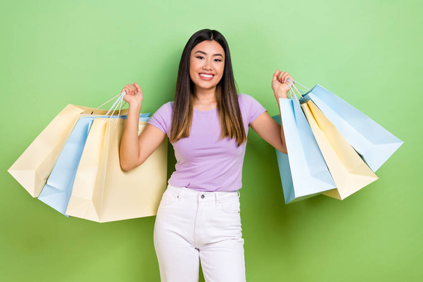 Photo of lovely japanese korean young lady hold shopping bags shopper wear trendy purple garment isolated on green color background. - Photo, Image