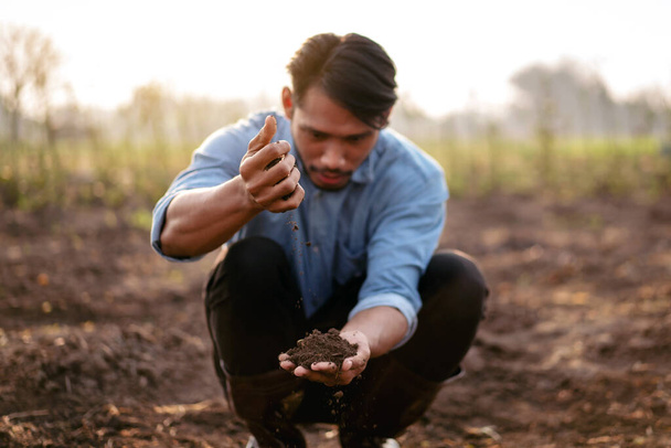 Chytrý zemědělec, který drží půdu ve svých rukou, aby prozkoumal kvalitu půdy pro kontrolu pracovního a plánovacího systému před pěstováním zeleniny pomocí technologie na zemědělském poli. - Fotografie, Obrázek