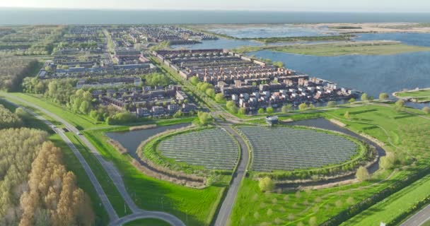 Suuressa mittakaavassa toimiva aurinkovoimala, jossa on maamerkkejä ja aurinkopaneeleja, tuottaa uusiutuvaa, puhdasta ja vihreää energiaa sähkön tuottamiseksi kaupunkitalouksille. Antenni drone video. - Materiaali, video