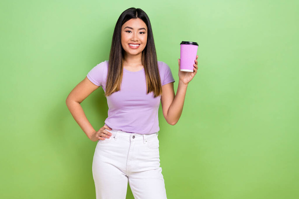 Photo of attractive japanese korean young woman hold pink paper cup coffee wear trendy purple clothes isolated on green color background. - Photo, image