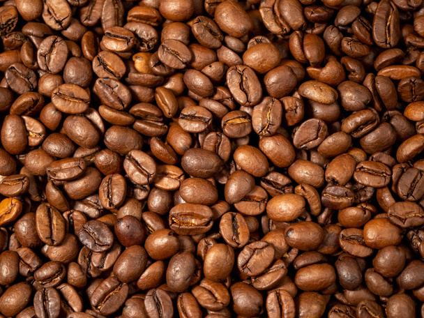 Hintergrund sind geröstete Kaffeebohnen. Verstreute Kaffeebohnen. Kaffeebohnen aus nächster Nähe. - Foto, Bild