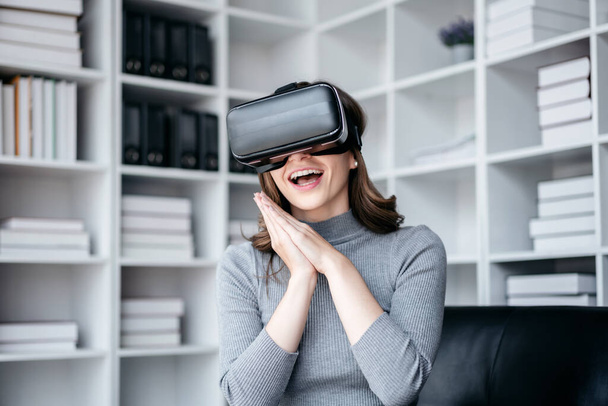 Businesswoman with vr headset lifestyle concept, Businesswoman wearing VR headset to playing game and touching experience virtual reality while relaxation with technology after working. - Photo, Image