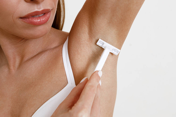 Closeup of female shaving armpits, removing underarms hair with razor. High quality photo - Φωτογραφία, εικόνα