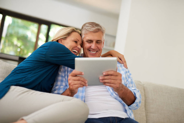 Voyons ce qui se passe ce week-end... un couple d'âge mûr utilisant une tablette numérique ensemble à la maison - Photo, image