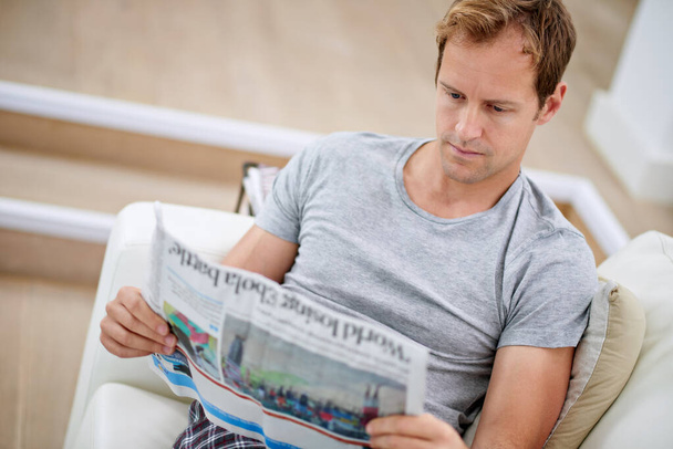 Sohva Times. komea mies istuu sohvalla sanomalehden kanssa - Valokuva, kuva