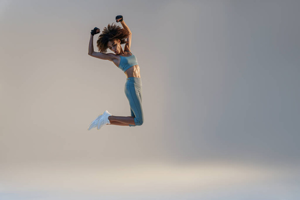 Athletic active woman jumping on studio background. Dynamic movement - Fotografie, Obrázek