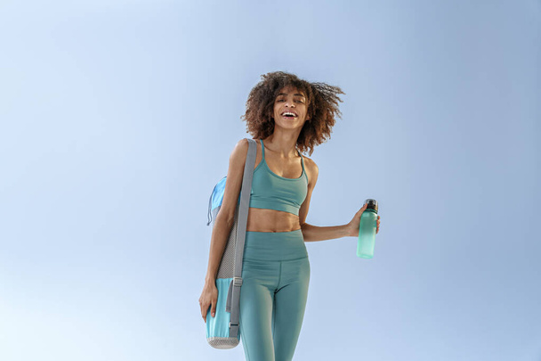 Woman with sports bag and bottle of water after training on studio background. High quality photo - Fotó, kép