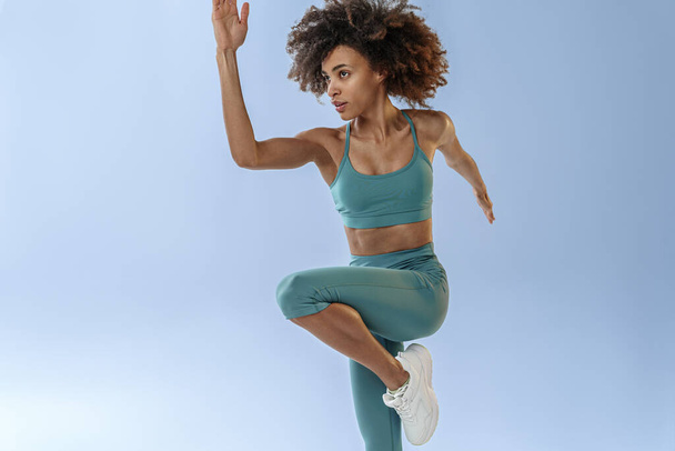 Athletic active woman jumping on studio background. Dynamic movement - Foto, imagen