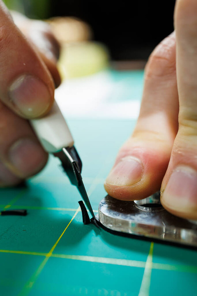 Las manos del maestro cosen productos de cuero hechos a mano. Las manos de los hombres conectan las piezas, creando accesorios de cuero de calidad. Proceso de trabajo en un taller de cuero - Foto, Imagen