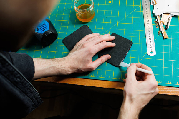 Руки профессионального мастера делают кожаный бумажник новый, чистый подлинный кожаный бумажник, крупным планом обрезанный выстрел. - Фото, изображение