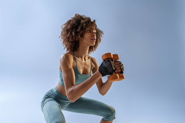 Woman doing exercises with dumbbells on studio background. Sport and healthy lifestyle - 写真・画像
