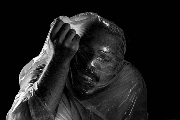 Hombre con bolsa de plástico en la cabeza, asfixiado. Tiro blanco y negro. expresión del dolor. - Foto, imagen