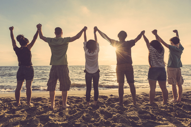 Multiracial group of people with raised arms looking at sunset - Photo, Image