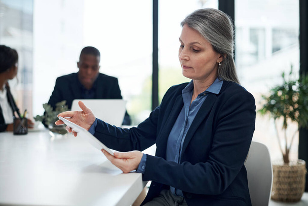 Une gestion de projet qui a un impact. une femme d'affaires mature utilisant une tablette numérique lors d'une réunion dans un bureau moderne - Photo, image