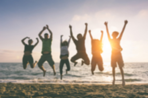Group of people jumping at beach, blurred background. - Photo, Image