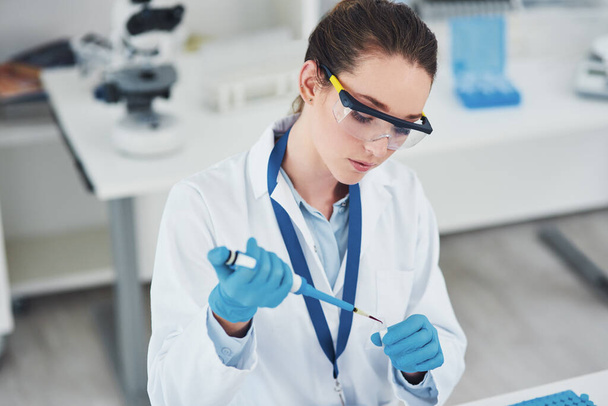 Ještě jedna kapka. soustředěná mladá vědkyně s ochrannými brýlemi při nalévání zkušebního vzorku do ohavného vnitřku laboratoře - Fotografie, Obrázek