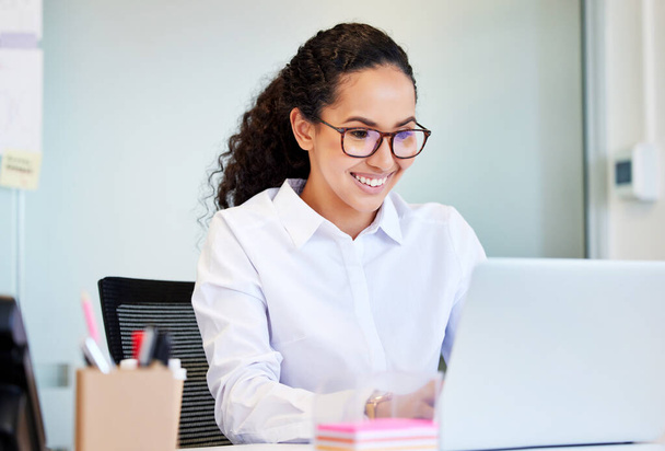 A enviar boas notícias a um cliente. uma atraente jovem empresária sentada sozinha no escritório e usando seu laptop - Foto, Imagem