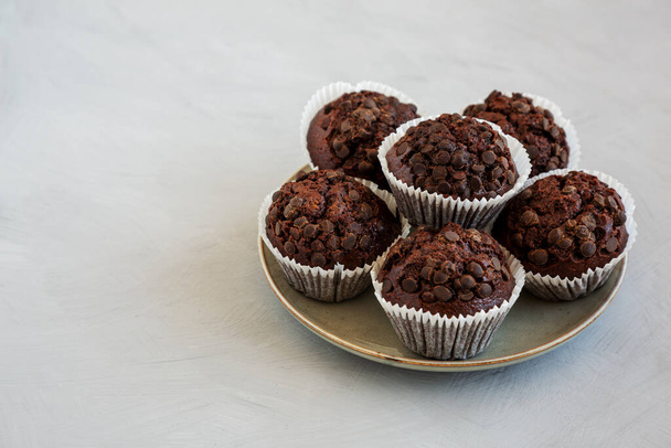 Hausgemachte dunkle Schokolade-Muffins auf einem Teller, Seitenansicht. Raum für Text. - Foto, Bild
