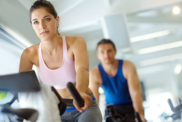 Toning those legs. A man and woman exercising in spinning class at the gym - Foto, Imagen