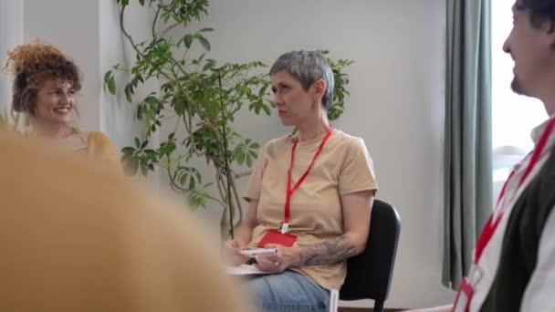 Grupa ludzi siedzących w kręgu z dwoma terapeutami i kobietą w centrum, dyskutującą i zapewniającą jej wsparcie emocjonalne. - Materiał filmowy, wideo
