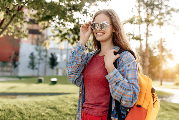 Joyful young blonde hipster woman student with backpack looking away with happy face - Foto, afbeelding