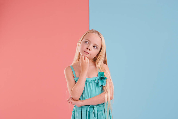 Hmmm, qué hacer a continuación.... Una niña linda contra un fondo colorido de dos tonos - Foto, Imagen
