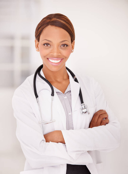 Do you have a good medical aid. A portrait of an ethnic female doctor with her arms folded and smiling at the camera - Foto, imagen