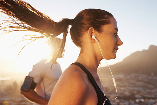 Sunrise, streaming and woman running as exercise or morning workout for health and wellness together. Sport, man and runner run with athlete while training and listening to sports music for energy. - Φωτογραφία, εικόνα