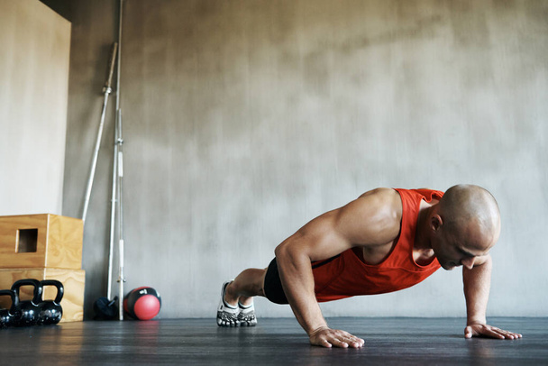 Workout, muscular and man doing gym studio push up for exercise, health performance and sports training for muscle building. Bodybuilding routine, determination or strong person doing floor pushup. - Photo, Image