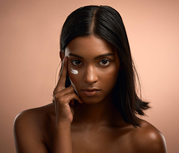 Aint shady baby, Im hot. Portrait of an attractive young woman applying moisturiser against a brown background - Fotó, kép