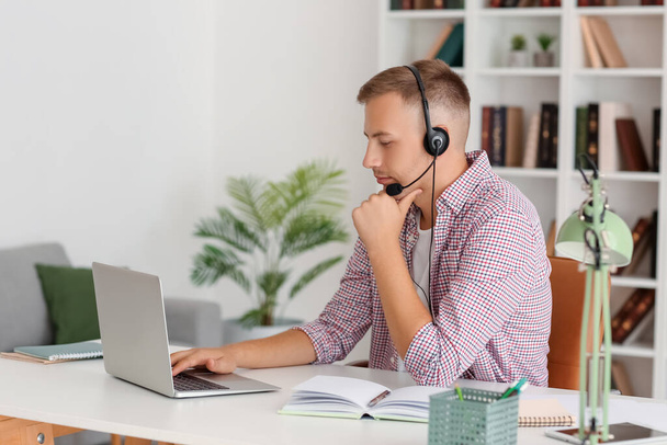Mladý muž se sluchátky a notebookem studuje on-line doma - Fotografie, Obrázek