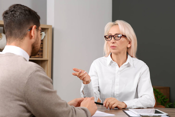 Boss and employee discussing work issues at wooden table in office - Photo, Image