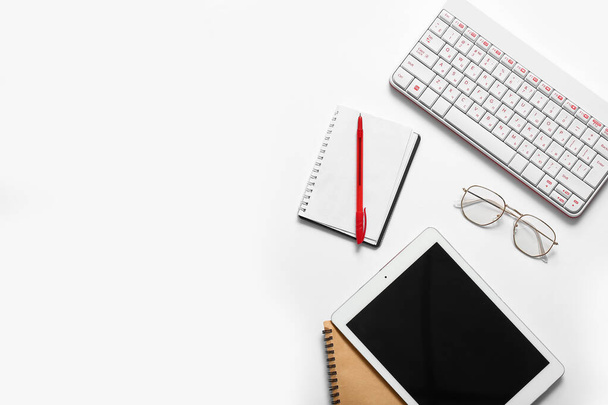 Kompozice s tabletem, notebookem, klávesnicí a brýlemi na bílém pozadí - Fotografie, Obrázek