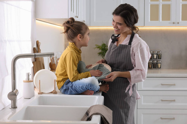 Young mother and her daughter spending time together in kitchen - Photo, image