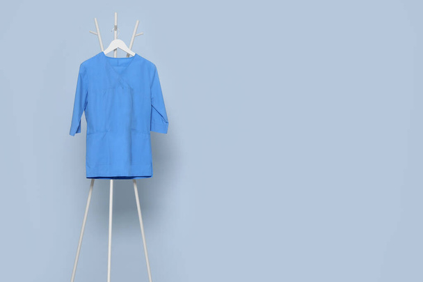 Blue medical uniform hanging on rack near light grey wall indoors. Space for text - Foto, immagini