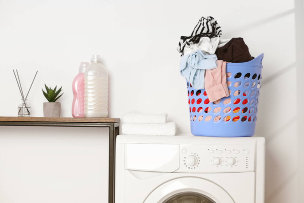 Laundry basket overfilled with clothes on washing machine in bathroom - Photo, image