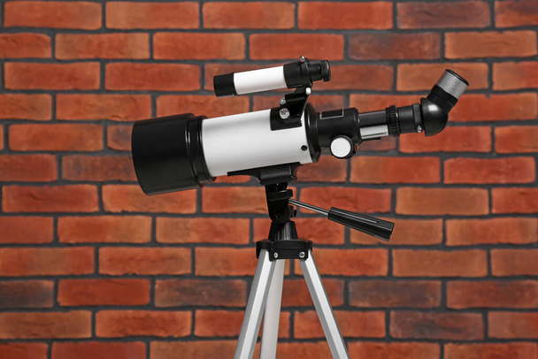 Tripod with modern telescope near brick wall - Foto, immagini