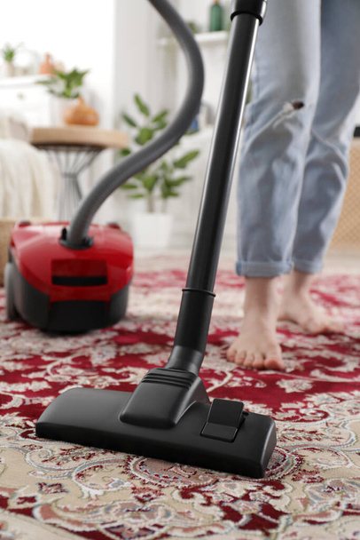 Woman cleaning carpet with vacuum cleaner at home, closeup - Fotografie, Obrázek